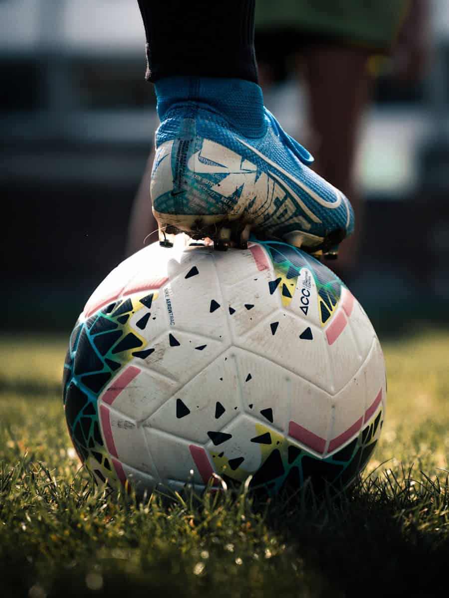 Photo by Connor Coyne white and blue soccer ball on green grass field
