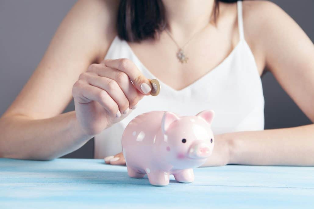 Woman putting a coin in a piggy bank